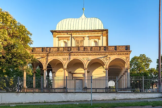 Das Königliche Lustschloss in den Gärten der Prager Burg, ein Renaissancepavillon mit grüner Kupferkuppel, einer Bogenloggia und einem Eisengeländer, im warmen Abendlicht.