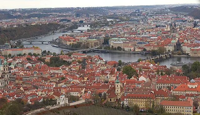 Panoramablick über Prags rotbedachte Altstadt, mit der sich durch die Stadt windenden Moldau, ihren Brücken über den Fluss und Kirchtürmen über den Dächern.
